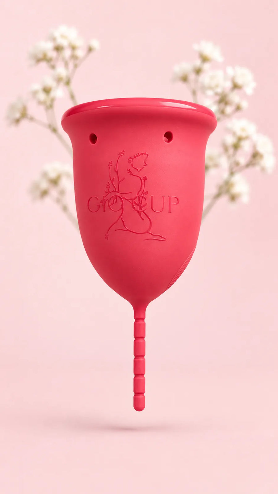 Copo menstrual GIOCUP® Rose suspenso sobre fundo cor-de-rosa, entre ramos de gipsófila