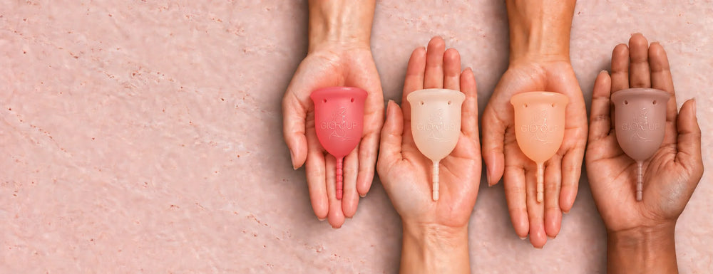 Four hands holding the GIOCUP® Rose, Pearl, Amber and Agate menstrual cups