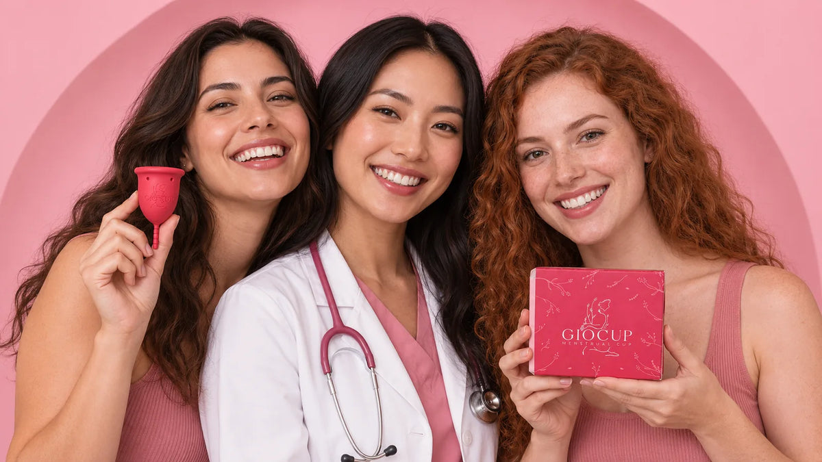 Três mulheres sorridentes em fundo rosa, uma de bata branca, com um copo menstrual GIOCUP® Rose e a embalagem vermelha